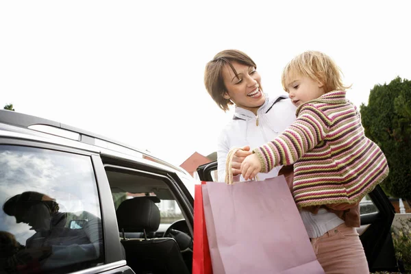 Mulher Carregando Sua Filha Enquanto Segurando Sacos Compras — Fotografia de Stock