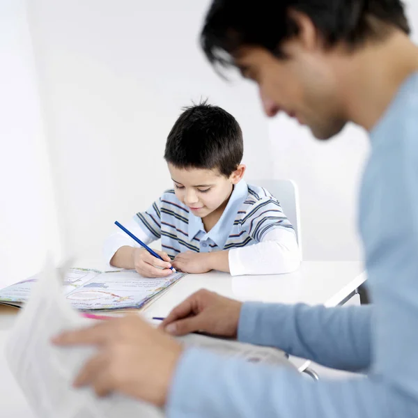 Far Läser Tidningen Med Son Gör Läxor Bakgrunden — Stockfoto