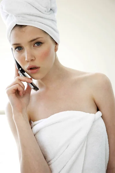 一个女人 头发和身体裹在毛巾里 用手机交谈 — 图库照片