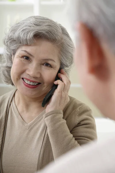 Μια Ηλικιωμένη Που Μιλάει Στο Τηλέφωνο Ένας Ηλικιωμένος Που Παρακολουθεί — Φωτογραφία Αρχείου