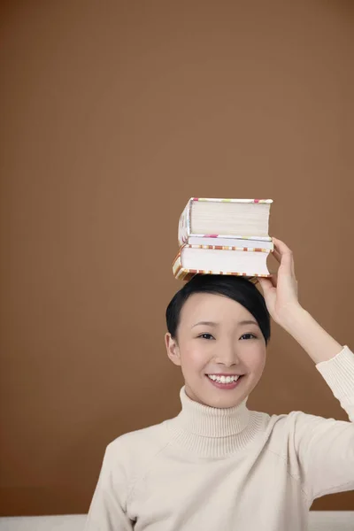 Een Vrouw Die Een Stapel Boeken Haar Hoofd Legt — Stockfoto