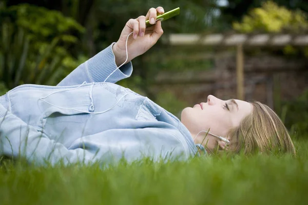 Dziewczyna Słucha Muzyki Leżąc Trawie — Zdjęcie stockowe