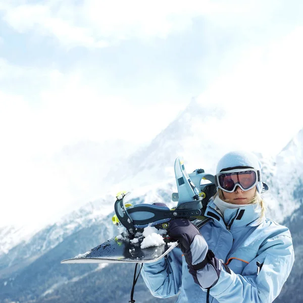 Woman in ski goggles holding snowboard