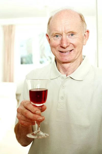 Senior Man Glimlachend Terwijl Hij Een Glas Rode Wijn Vasthoudt — Stockfoto