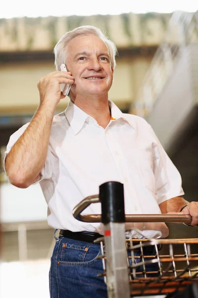Άνθρωπος Πιέζει Καλάθι Αποσκευών Ενώ Μιλάμε Στο Τηλέφωνο Στο Αεροδρόμιο — Φωτογραφία Αρχείου