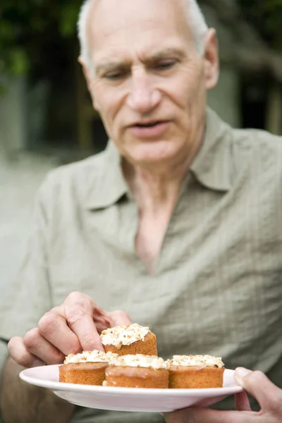 Senior man taking a piece of cake from plate