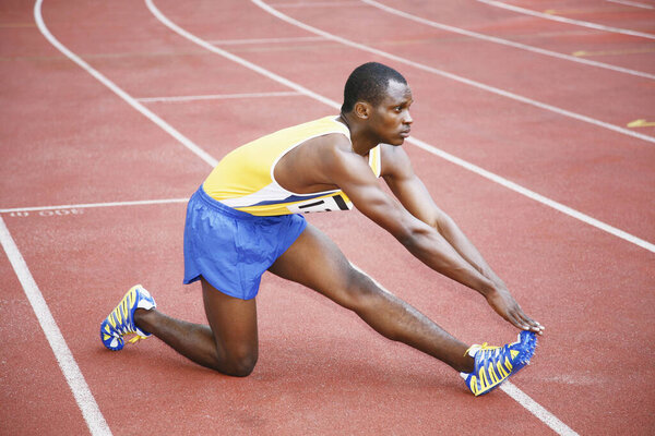 Man stretching his leg on running track