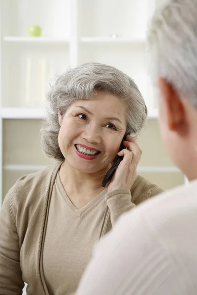 Μια Ηλικιωμένη Που Μιλάει Στο Τηλέφωνο Ένας Ηλικιωμένος Που Παρακολουθεί — Φωτογραφία Αρχείου