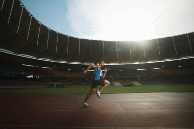 Pistte koşan bir adam, yarış için ısınıyor.