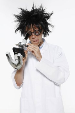 Laboratuvar önlüklü bir adam mikroskoptan bakıyor.