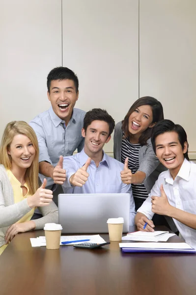 Business people smiling at the camera with thumbs up