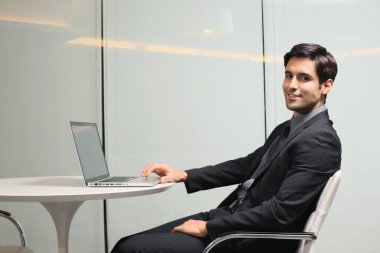 İş adamı dizüstü bilgisayar kullanıyor ve gülümsüyor