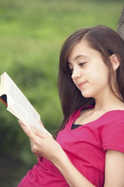 Dışarıda kitap okuyan bir kız.