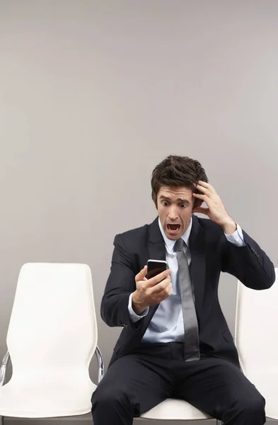 Businessman looking disappointed after reading text messages on mobile phone