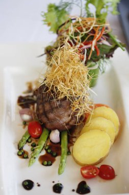 Kızarmış biftek, dilimlenmiş patates ve kuşkonmaz.