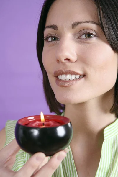 Woman holding lit scented candle