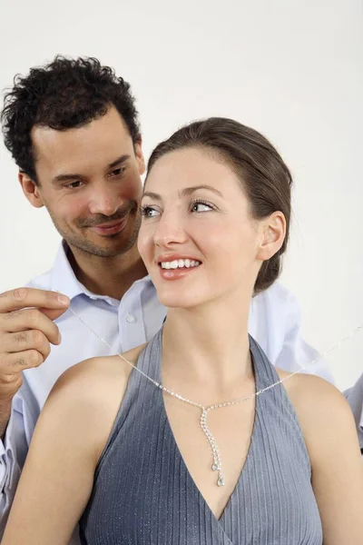 Man putting on a necklace for his girlfriend