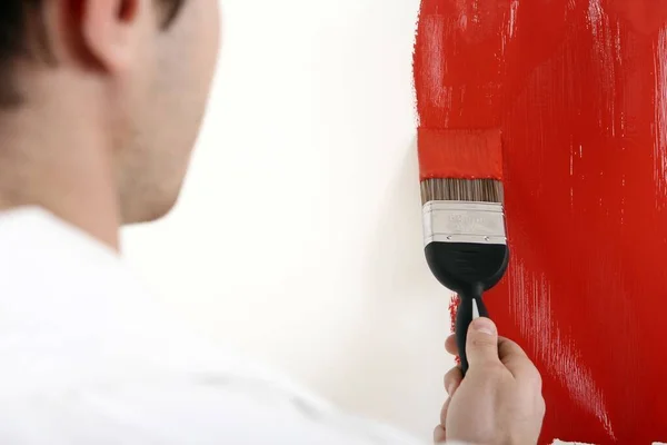 Man painting the wall red