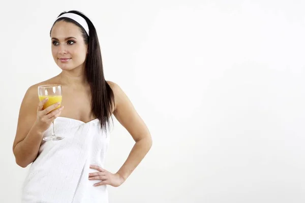 女人拿着一杯橙汁裹在毛巾里 — 图库照片