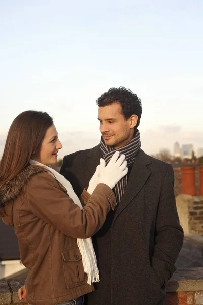 Woman adjusting man\'s scarf at the rooftop