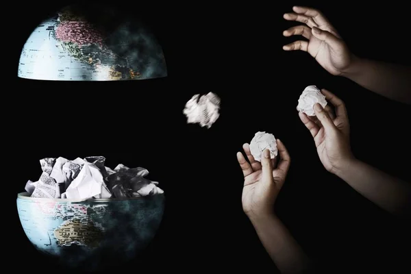 Human hand throwing crumpled paper into the center of globe