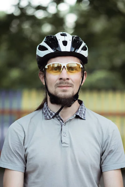 Close up tiro de feliz atraente jovem com barba vestindo capacete protetor e óculos de sol amarelos olhando para a câmera — Fotografia de Stock
