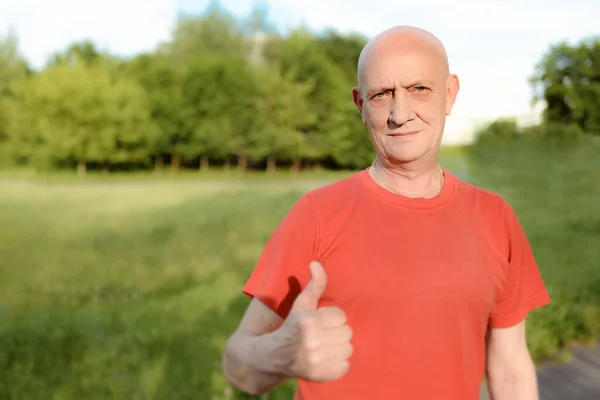 Senior man in casual wear stands smiling and showing thumb up to camera — Stock Photo, Image