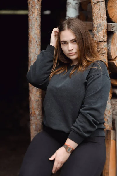 Skott av en attraktiv ung kvinna sitter framför trä bakgrund — Stockfoto