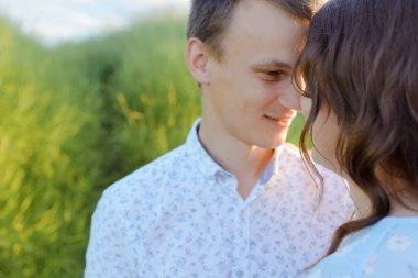 Hamile kadın gün batımında kocasıyla öpüşüyor..