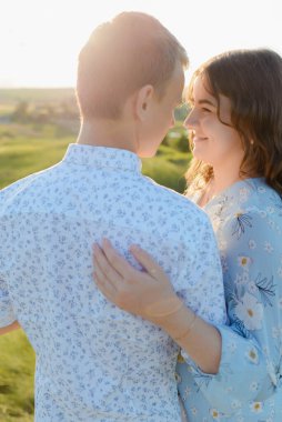 Gelecekteki anne ve baba gün batımında parkta öpüşecekler.