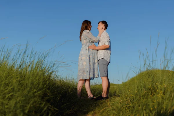 Feliz joven pareja besándose en la cima de una montaña, con el cielo despejado en el fondo —  Fotos de Stock