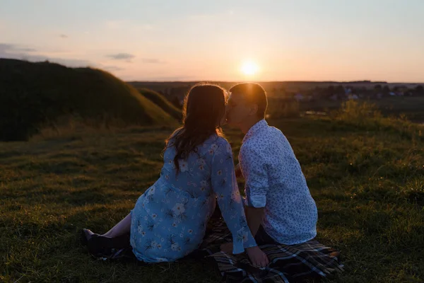 Pareja cariñosa, un chico y una chica se besan y abrazan al atardecer —  Fotos de Stock