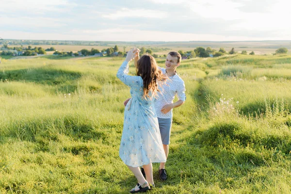 Joven pareja alegre de hombre y mujer al aire libre en un campo, abrazando y bailando —  Fotos de Stock