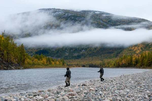 Pesca do pescador girando na margem do rio floresta selvagem. — Fotografia de Stock