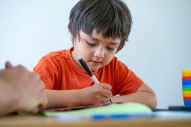 Kırpılmış küçük çocuk kalem kullanıyor, baba oğluna ödevlerinde yardım ediyor, öğretmen küçük çocuğa nasıl yazılacağını öğretiyor. evde eğitim kavramı