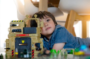 Liseli çocuğun portresi halıya uzanıp askerlerle, arabalarla ve biblo oyuncaklarıyla oynamak, Mutlu Çocuk 'un evde tek başına savaş ve barış oynaması, çocukların hayal gücü ve gelişimi. 