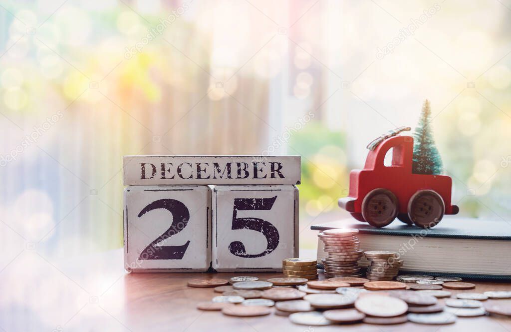 Wooden Christmas calendar.December 25th with stacks pound coin and red car toy with Christmas tree,Financial planing for New normal ready before New Year resolution for saving money,Holiday background