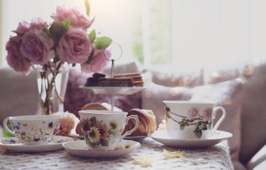 Geleneksel İngiliz çay saati, öğleden sonra çay seremonisi çay, kruvasan, kraker ve bisküvi pembe pastel çay standında. Konservatuar odasında öğleden sonra partisinin samimi havası
