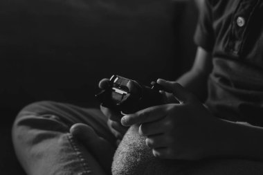 Siyah ve beyaz Çocuk Eller video oyunu veya oyun konsolu tutuyor. Oyun oynayan çocuk okul kapanırken evde kalıyor, karantina ve sosyal uzaklık ya da kendini izole etme kavramı