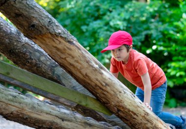 Foest Park 'ta bir ağaç eve tırmanan portreli aktif bir çocuk yazın oyun parkında oynayan bir çocuk. Yaz tatili kavramı
