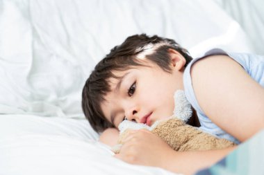  7 yaşında bir çocuk yatakta yatıyor, uykucu çocuk sabah uykusunda uyanıyor, küçük tatlı bir çocuk köpek oyuncağıyla uyuyor. Çocuk sağlığı hizmetleri ya da gençken uyku sorunları