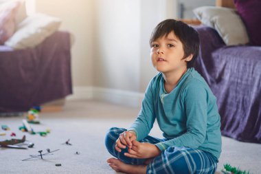 Mutlu çocuk halıda oturup oturma odasında askerlerle ve oyuncaklarla oynuyor, seçici odaklı çocuk evde kendi kendine savaş ve barış oynuyor, çocukların hayal gücü ve gelişimi. 