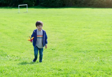 Yeşil doğaya karşı oyuncak uçakla oynayan portre, yeşil alana köpük atan çocuk, parkta oynayan çocuk, açık hava aktivitesi konsepti.