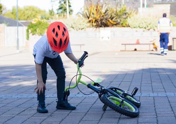 High key portrait of young boy try to picking up his his bike up from the floor,  School kid learns to ride a bike.