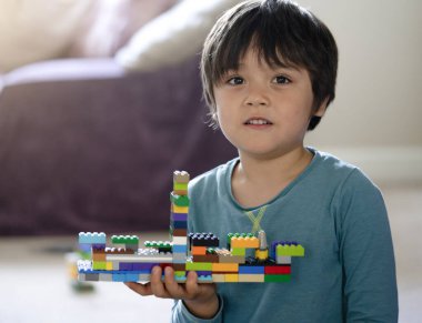 Plastik oyuncak bloklarıyla oynayan aktif çocuk, evde renkli oyuncaklarla oynayan çocuğun seçici odağı, bebek gelişimi konsepti.