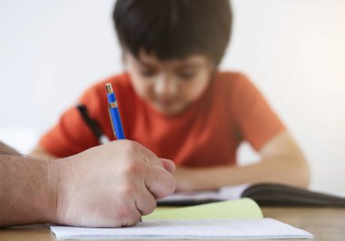 Kırbaçlanmış baba oğluna ödevlerinde yardım ediyor, baba ve oğul birlikte ödev yapıyor, öğretmen küçük çocuğa nasıl yazılacağını öğretiyor. Erkek eli kalem, eğitim kavramı
