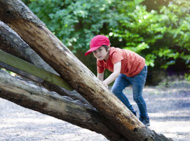 Foest Park 'ta bir ağaç eve tırmanan portreli aktif bir çocuk yazın oyun parkında oynayan bir çocuk. Yaz tatili kavramı