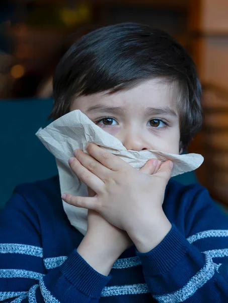 Sick kid blowing nose into tissue, Unhealthy child suffering from running nose or sneezing and covering his nose and mouth, A boy catches a cold when season change, childhood wiping nose with tissue