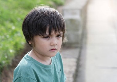 Kayıp çocuk, güneşli yaz gününde düşünen yüzüyle dışarı bakıyor endişeli yüzüyle yeşil çimenlerin bulanık geçmişiyle Yükseklik Anahtarı tasvir eden çocuk, kayıp çocuk konsepti.