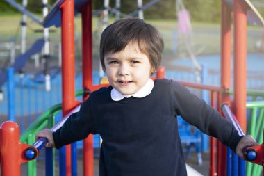 Okul çocuğu, çocuk parkında mutlu bir yüzle oyun oynuyor, çocuk parkında oynuyor, çocuklar için açık hava aktiviteleri yapıyor.